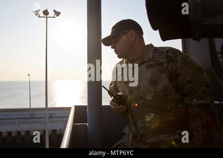 Chief Warrant Officer 4 Ned Walsh, Skipper mit den 411 Transport Loslösung, fordert in der Lenkung Richtungen und Motorleistung Anweisungen an seine Crew beim Verlassen des Hafens während an Bord der Logistik Support Vessel - 5 (LSV-5) "MG Charles S. Brutto" im Arabischen Golf, Jan. 24, 2017. (U.S. Armee Foto: Staff Sgt. Dalton Smith) Stockfoto