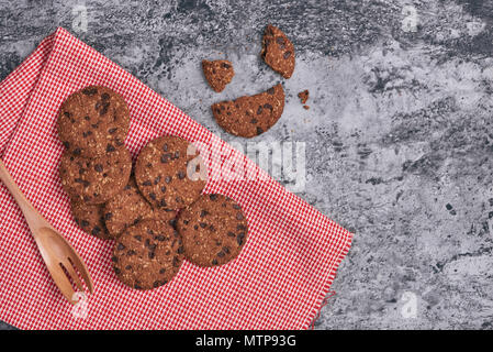 Chocolate Chip Cookies auf Leinen Serviette auf Tisch aus Stein. Gestapelte Chocolate Chip Cookies. Stockfoto