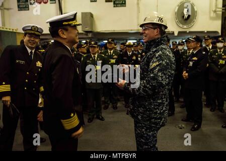 180123-N-OY 799-058 Yokosuka, Japan (Jan. 23, 2018) Kapitän Buzz Donnelly, kommandierender Offizier der Marine vorwärts - bereitgestellt Flugzeugträger USS Ronald Reagan (CVN 76), Austausch Geschenke mit Vice Adm. Katsuto Deguchi, Kommandant, Joint Staff College, während einer Tour im Hangar Bay. Ronald Reagan, das Flaggschiff der Carrier Strike Group 5, bietet eine Bekämpfung bereit, Kraft, schützt und verteidigt die kollektive maritime Interessen seiner Verbündeten und Partnern in der Indo-Asia-Pazifik-Region. (U.S. Marine Foto von Mass Communication Specialist 2. Klasse Kenneth Abbate / freigegeben) Stockfoto