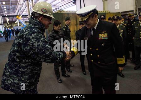 180123-N-OY 799-031 Yokosuka, Japan (Jan. 23, 2018) Kapitän Buzz Donnelly, kommandierender Offizier der Marine vorwärts - bereitgestellt Flugzeugträger USS Ronald Reagan (CVN 76), grüßt Vice Adm. Katsuto Deguchi, Kommandant, Joint Staff College, während einer Tour im Hangar Bay. Ronald Reagan, das Flaggschiff der Carrier Strike Group 5, bietet eine Bekämpfung bereit, Kraft, schützt und verteidigt die kollektive maritime Interessen seiner Verbündeten und Partnern in der Indo-Asia-Pazifik-Region. (U.S. Marine Foto von Mass Communication Specialist 2. Klasse Kenneth Abbate / freigegeben) Stockfoto