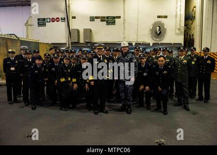 180123-N-OY 799-073 Yokosuka, Japan (Jan. 23, 2018) Kapitän Buzz Donnelly, kommandierender Offizier der Marine vorwärts - bereitgestellt Flugzeugträger USS Ronald Reagan (CVN 76), posiert für ein Foto mit Joint Staff College Studenten während einer Tour im Hangar Bay. Ronald Reagan, das Flaggschiff der Carrier Strike Group 5, bietet eine Bekämpfung bereit, Kraft, schützt und verteidigt die kollektive maritime Interessen seiner Verbündeten und Partnern in der Indo-Asia-Pazifik-Region. (U.S. Marine Foto von Mass Communication Specialist 2. Klasse Kenneth Abbate / freigegeben) Stockfoto