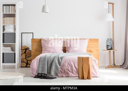 Holzdekor geräumiges Schlafzimmer mit rosa Bettwäsche und weißen Wänden Stockfoto