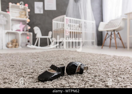 Schuss schwarzen Baby Schuhe auf einem Teppich in einer Baumschule Stockfoto