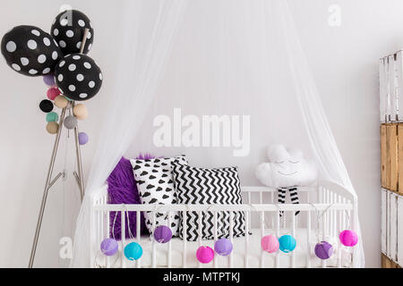 Little Baby Princess Wiege in Weiß Schlafzimmer. In der Ladestation Schwarz, Weiß und Violett Kissen Stockfoto