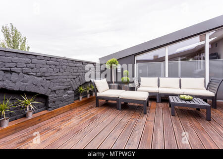 Äpfel in Schale auf schwarzen hölzernen Tisch auf der Terrasse mit Gartenmöbeln und Wand Stockfoto