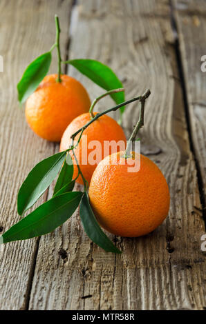 Drei Reife Mandarinen auf dunklen Holztisch Stockfoto