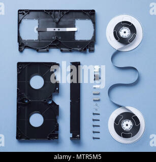 Komponenten einer VHS-Kassette zerlegt und gut über blauen Hintergrund angeordnet Stockfoto