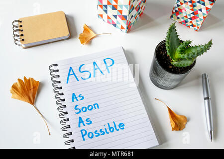 ASAP so bald wie möglich in einem Notebook auf weißem Tabelle geschrieben Stockfoto