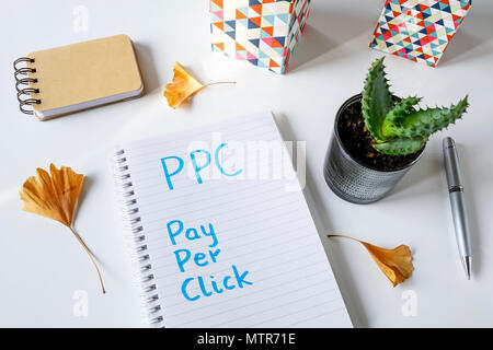PPC Pay Per Klick in ein Notizbuch auf weißem Tabelle geschrieben Stockfoto
