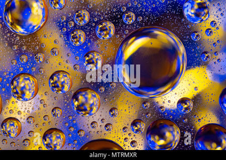 Wassertropfen auf Glas mit Gelb und Gold beleuchteten Hintergrund Stockfoto