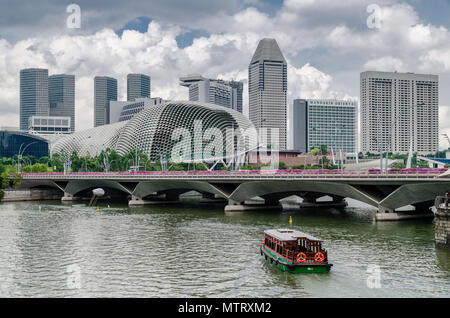 Eine Kreuzfahrt Boot wie die twakows Fahrt durch die berühmten Singapore River bekannt. Das Gebäude an der Rückseite ist die berüchtigte Theater an der Bucht, Esplanade. Stockfoto