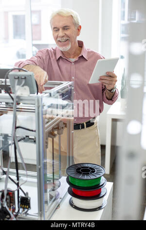 Freudige älterer Mann lernen, wie 3D-Drucker verwenden Stockfoto