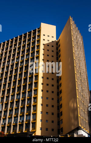 Ein altes Büro, gelbes Gebäude mit ungewöhnlicher Form mit klaren blauen Himmel Hintergrund. Stockfoto