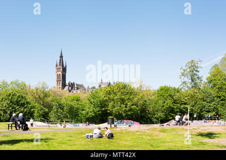 Die Menschen genießen einen warmen sonnigen Tag auf dem Rasen des Kelvingrove Park, Kelvingrove Art Gallery und Museum im Hintergrund Stockfoto