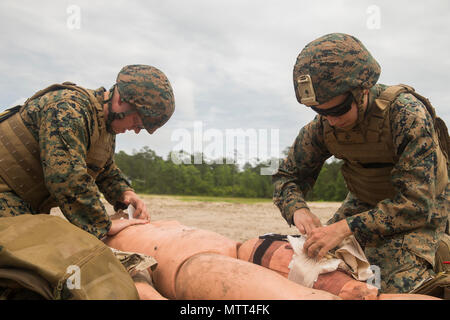 Petty Officer 2nd class Anna Raykiewicz, Hospital corpsman, 22 Marine Expeditionary Unit, gilt ein stauschlauch bei einem simulierten Unfall während einer taktischen Evakuierung Kurs in Camp Lejeune, N.C., 23. Mai 2018. Die taktische Evakuierung Kurs ausgebildet Hospital corpsman die korrekten Techniken in ungewöhnlichen Evakuierung Umgebungen zu verwenden. (U.S. Marine Corps Foto von Lance Cpl. Tawanya Norwood) Stockfoto