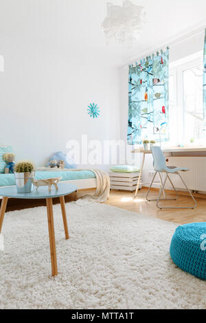 Sehr helle und geräumige Teenager Zimmer mit großen, flauschigen Teppich, einem Couchtisch und einem blauen tuffet Stockfoto