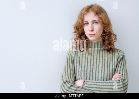 Portrait der verschlimmerten traurige Frau mit langen roten Haaren mit gekreuzten Händen ihre Unzufriedenheit zum Ausdruck zu bringen und disconent. Stockfoto