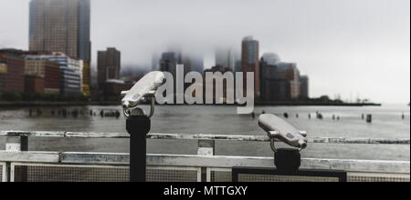 Zwei Sucher mit Blick auf Lower Manhattan, wie er im Nebel bedeckt ist. Stockfoto