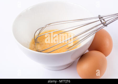 Rühren, Eier in der Schale. Vorbereitung Omelett mit Schneebesen und Eier auf weißem Schreibtisch in der Küche. Kochen und Essen. Close Up, selektiver Fokus Stockfoto