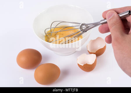 Koch hand Eier rühren in Weiß Schüssel auf Küche weißer Tisch. Kochen und Essen. Nahaufnahme Stockfoto