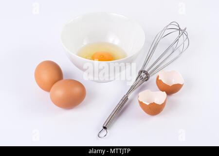 Eiweiß mit dem Eigelb in kleine Schüssel und andere Einträge Eier mit einem Rühren auf weißem Hintergrund. Essen und Kochen Konzept Stockfoto