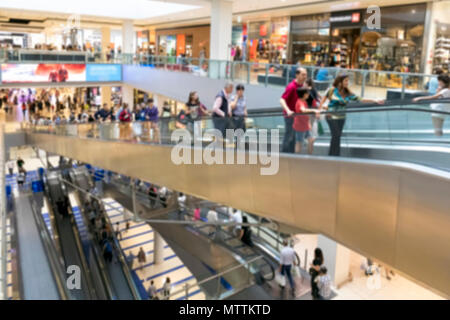 Menschen gehen Einkaufen im Shopping Center. Die Räume mit den verschiedenen Geschäfte sind auf mehreren Etagen durch lange Rolltreppen verbunden entwickelt. verschwommen Stockfoto
