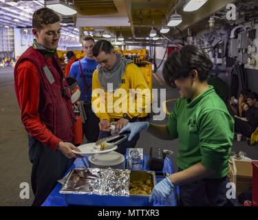 180516-N-AC 117-0086 GEWÄSSER SÜDLICH VON JAPAN (16. Mai 2018) Kulinarische Specialist Seaman Kate Millanayala, aus Las Vegas, serviert im Hangar Bucht der Marine vorwärts - bereitgestellt Flugzeugträger USS Ronald Reagan (CVN 76), während eine Auffüll-anforderung-auf-See mit Military Sealift Command (MSC) Dry Cargo/Munition ship USNS Cesar Chavez (T-AKE 14), 16. Mai 2018. Die nicht-Kämpfer, zivil-Crewed Charter Schiff, vom MSC betrieben, Benzin, Essen, Kampfmittel, Ersatzteile, Mail und andere Verbrauchsmaterialien zur Marine Schiffen in der ganzen Welt. Ronald Reagan, das Flaggschiff der Carrier Strike Group 5, bietet eine Bekämpfung - Lesen Stockfoto