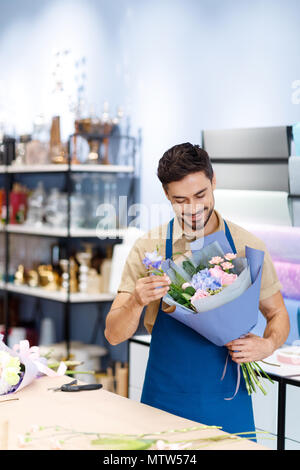 Lächelnd Mann florist Anordnen von Blumen im Strauß während in Flower Shop arbeiten Stockfoto