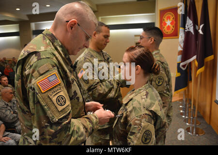 Brig. Gen. Jeffrey Johnson, Brooke Army Medical Center kommandierender General, stellt SPC. Bretagne Lopez, Armee Healthcare Spezialist, mit einem schwarzen Abzeichen Befehl als Sgt. Maj. Albert Mannschaften präsentiert Staff Sgt. Alfredo Herrera jr., noncommissioned Officer verantwortlich für 2 Ost, seine schwarze Abzeichen während der 68W-Nutzung Kick-off-Veranstaltung 14.01.17 In der 4. Etage Auditorium. Die schwarze Abzeichen bezeichnet die Träger besitzt die grundlegenden Fähigkeiten eines 68 W. (U.S. Armee Foto von Robert Schilde/Freigegeben) Stockfoto