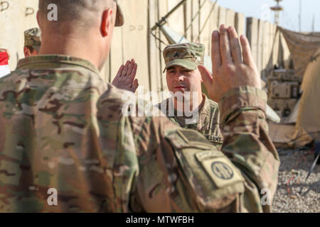 Oberstleutnant John Hawbaker, Kommandant der 1. Staffel, 73 Cavalry Regiment, 2nd Brigade Combat Team, 82nd Airborne Division, Fragen nach dem Eid des reenlistment zu Sgt. Patrick R. Bradford, ein infanterist, nach seiner dreijährigen reenlistment bei Qayyarah West, Irak, Jan. 26, 2017. Zur Unterstützung der Operation inhärenten lösen, die 2 BCT eingesetzt, 82. Abn. Div. ermöglicht, ihre irakische Sicherheitskräfte, die Partner durch den beraten und unterstützen die Mission, die die Planung, Erfassung und Analyse von Intelligenz, Kraft und Präzision Brände die militärische Niederlage der ISIL zu erreichen. (U.S. Armee Foto von St Stockfoto