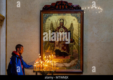 Ein Mann, der eine Kerze im Inneren der Kathedrale 1352, Pechersk Lavra Klosteranlage, Kiew, Ukraine Stockfoto