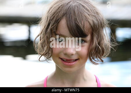 Portrait eines glücklichen jungen Mädchen mit fehlenden vorderen Zähne durch einen See Stockfoto