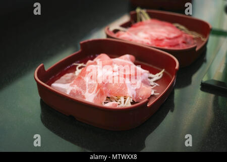 Raw filet Schwein und Rind in Scheiben geschnitten auf rotem Teller Stockfoto