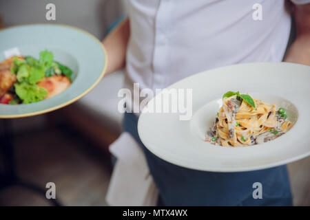 Nahaufnahme der Hand der Kellner serviert Spaghetti mit cremigen Soße im restaurant, essen und trinken Service Konzept, Stockfoto