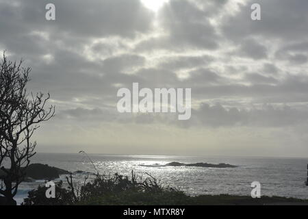 Der silberne Himmel, das Sonnenlicht, das durch die Wolken scheint und auf das Meer glitzert, sorgt für eine majestätische und dramatische Meereslandschaft über dem Pazifischen Ozean, Australien Stockfoto