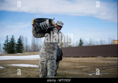 Us Air Force Airman 1st Class Jerred Davis, ein 354 Bauingenieur Squadron Pflaster- und Baumaschinen operator, trägt ein Schlauch April 10, 2017, at Eielson Air Force Base, Alaska. Während der Pause-Saison, Flieger im Schnee Scheune verwenden, um die Schläuche zu Wasser von der Flight Line, um sicherzustellen, dass die Flying Mission nicht betroffen ist. Stockfoto