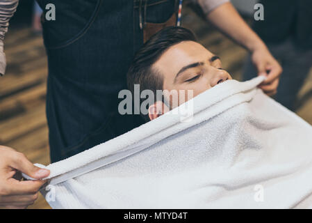 Client mit einem Handtuch vor dem Rasieren in Friseur Stockfoto