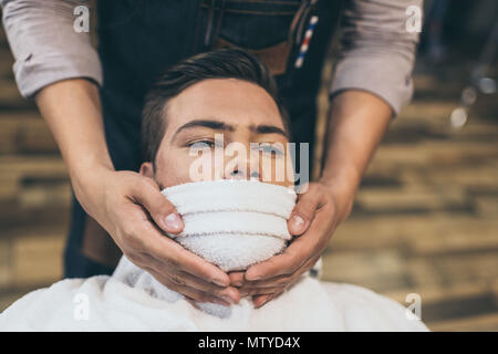 Client mit einem Handtuch vor dem Rasieren in Friseur Stockfoto