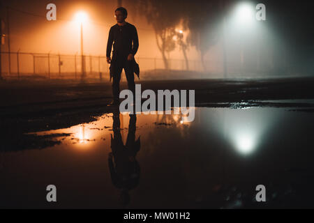 Mann, der nachts in der Straße bei einer Wasserpfütze steht, Kalifornien, USA Stockfoto