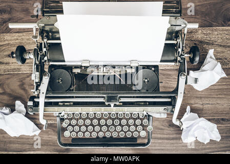 Blick von oben auf die alte Schreibmaschine und zerknittertes Blatt Papier auf rustikalen Holztisch Stockfoto