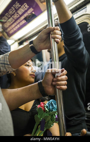 Mitfahrer teilen sich ein Pol für Balance, beim Reiten eines überfüllten uptown Rush Hour die U-Bahn in Midtown Manhattan. NYC. Stockfoto