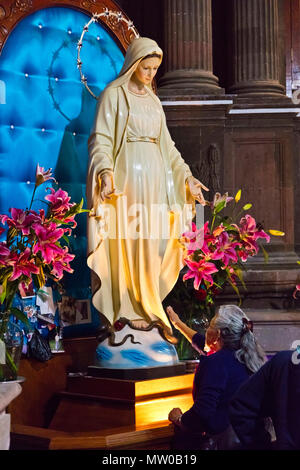 Eine katholische Frau verehrt, eine Statue der Jungfrau Maria am Karfreitag im Oratorium der Kirche Parroquia de SAN MIGUEL ACRCANGEL, SAN MIGUEL DE ALLE Stockfoto