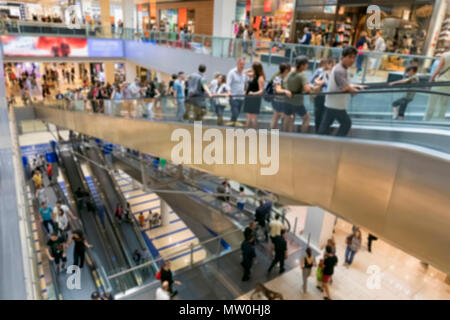 Menschen gehen Einkaufen im Shopping Center. Die Räume mit den verschiedenen Geschäfte sind auf mehreren Etagen durch lange Rolltreppen verbunden entwickelt. verschwommen Stockfoto