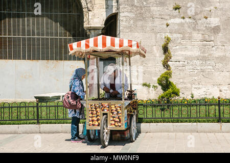 Editorial Bild der hübschen muslimischen Frau im hijab Einkauf geröstete Kastanien aus freundlich Straßenhändler in Istanbul Türkei am 15. Juni 2017. Stockfoto