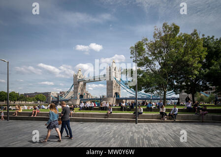 Mittagsstunde im Potters Fields Park, der Stadt London. Die Sonne scheint, als Arbeitskollegen im Hintergrund auf dem Gras mit Tower Bridge picknicken Stockfoto