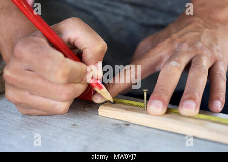 Nahaufnahme eines jungen kaukasischen Mann, eine Markierung mit einem Zimmermann Bleistift in einen Wald streifen Stockfoto