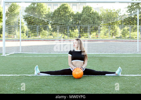 Junge Frau sitzt auf der Garn- und halte den Ball in den Händen. Stockfoto