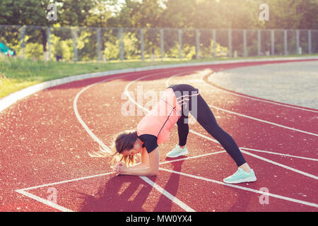 Junge Frau tun Gymnastik Training auf einem Sportplatz. Stockfoto