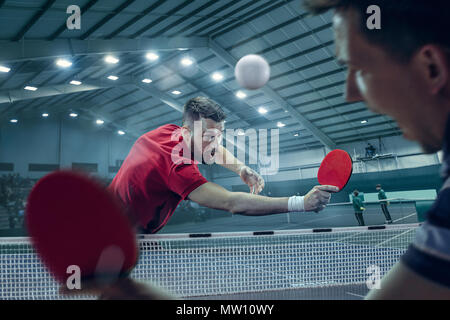 Die Tischtennis Spieler in Bewegung. Fit sport Mann Tennis-Spieler im Spiel auf Sport Arena Hintergrund mit Beleuchtung. Bewegung, Sport, Spiel, stobe conce Stockfoto