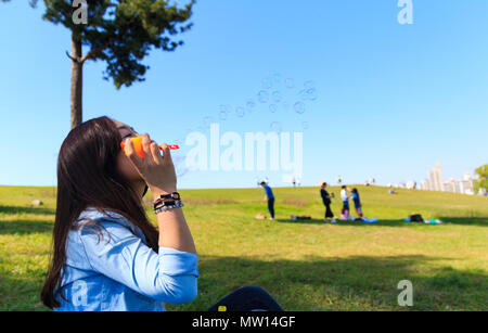 Asiatische junge Frau, die Blase im Park Stockfoto